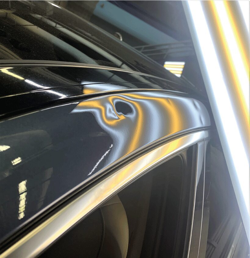 A dent on the outer top pillar of a car as part of a before and after slider